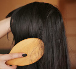 Female,hand,holds,a,black,wig,with,long,hair,and